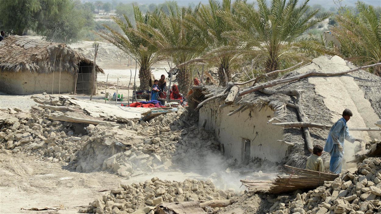 Des survivants du séisme au Baloutchistan enlèvent les décombres de leur maison, le 25 septembre 2013.