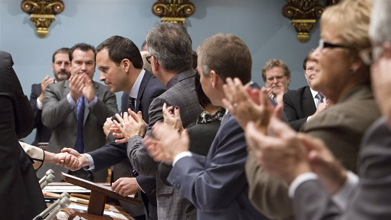 Les députés du Parti québécois applaudissent le ministre des Affaires intergouvernementales, Alexandre Cloutier, après la présentation de la motion blâmant le gouvernement fédéral pour son « intrusion » dans la démocratie québécoise, le 23 octobre 2013.