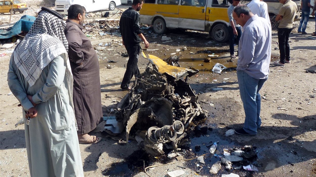 Des Irakiens inspectent la carcasse d’un véhicule à la suite d’un attentat commis dans le quartier Mashtal de Bagdad, le 27 octobre.