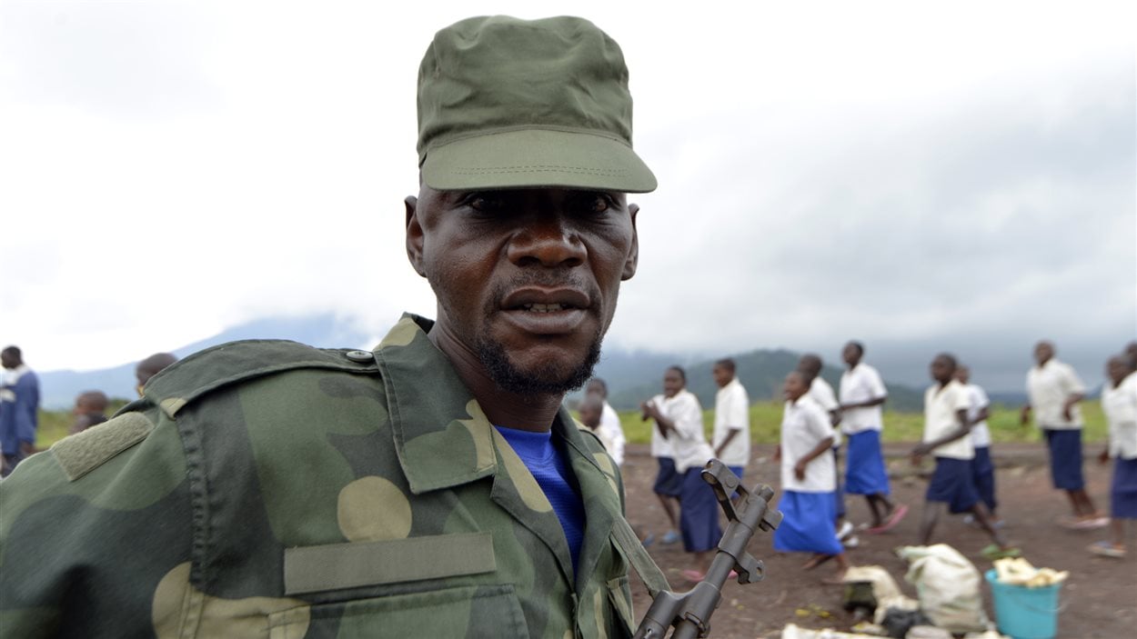 Un soldat de l'armée congolaise pose alors que des enfants chantent pour célébrer la victoire des forces gouvernementales.