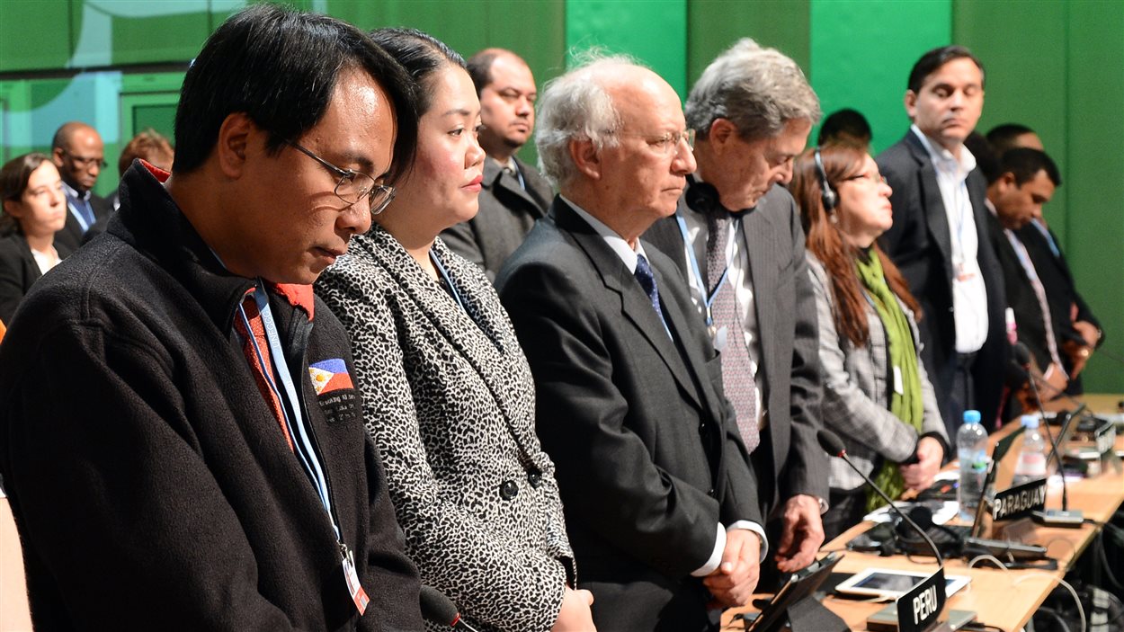 Les délégués ont observé une minute de silence à la mémoire des victimes du super-typhon Haiyan aux Philippines. À gauche, le délégué des Philippines Naderev Sano.