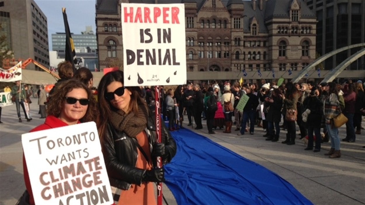 Deux manifestantes dénoncent les actions du gouvernement fédéral dans le dossier de l'énergie devant l'hôtel de ville de Toronto.