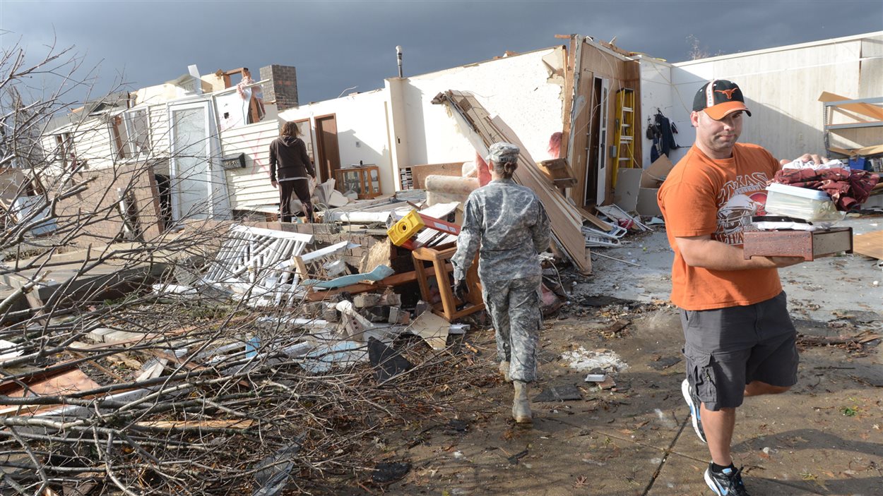 Des résidents de Washington, en Illinois, arpente les décombres à la suite du passage de dizaines de tornades.