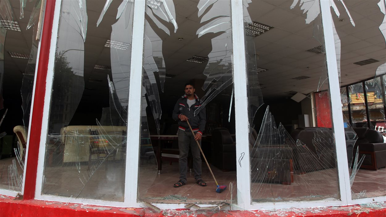 Un homme nettoye les débris des vitres qui ont éclaté sous la force d'une explosion.