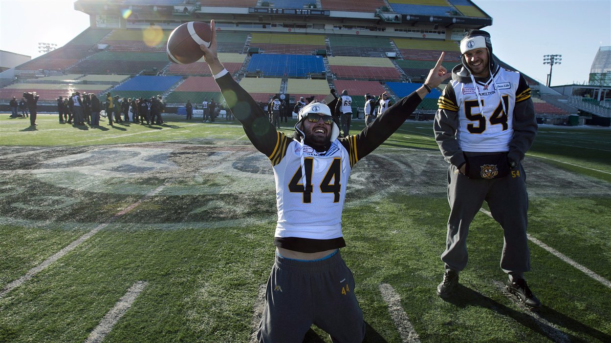 Le botteur de dégagement Josh Bartel (44) et le secondeur Kevin Scott (54) lors de la pratique des Tiger-Cats au stade Mosaic, la veille de la Coupe Grey.
