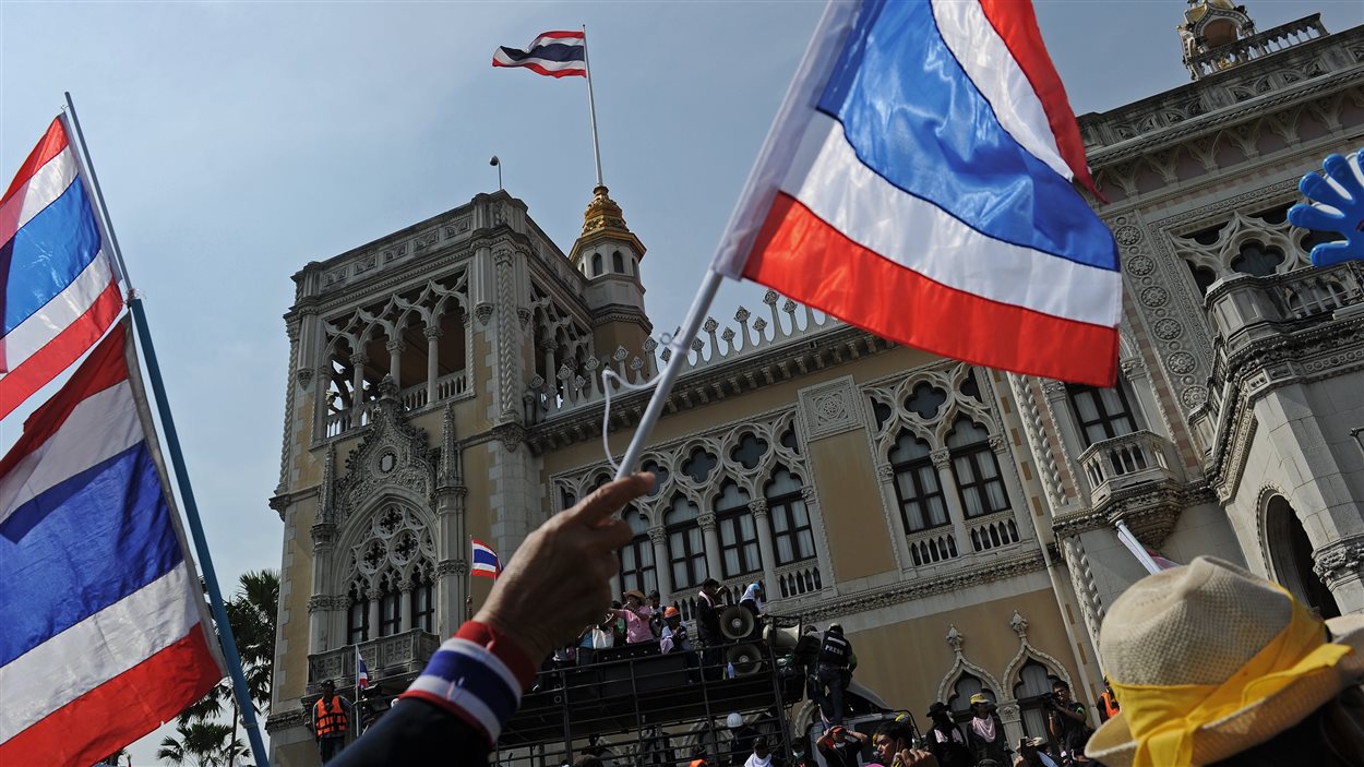 Un manifestant agite un drapeau de la Thaïlande devant le siège du gouvernement.
