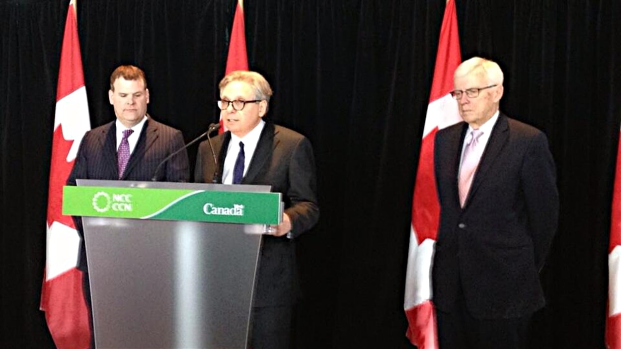 Le ministre responsable de la région de la capitale nationale, John Baird (à g.), a nommé Mark Kristmanson PDG de la CCN. À dr. le président de la CCN, Russell Mills.