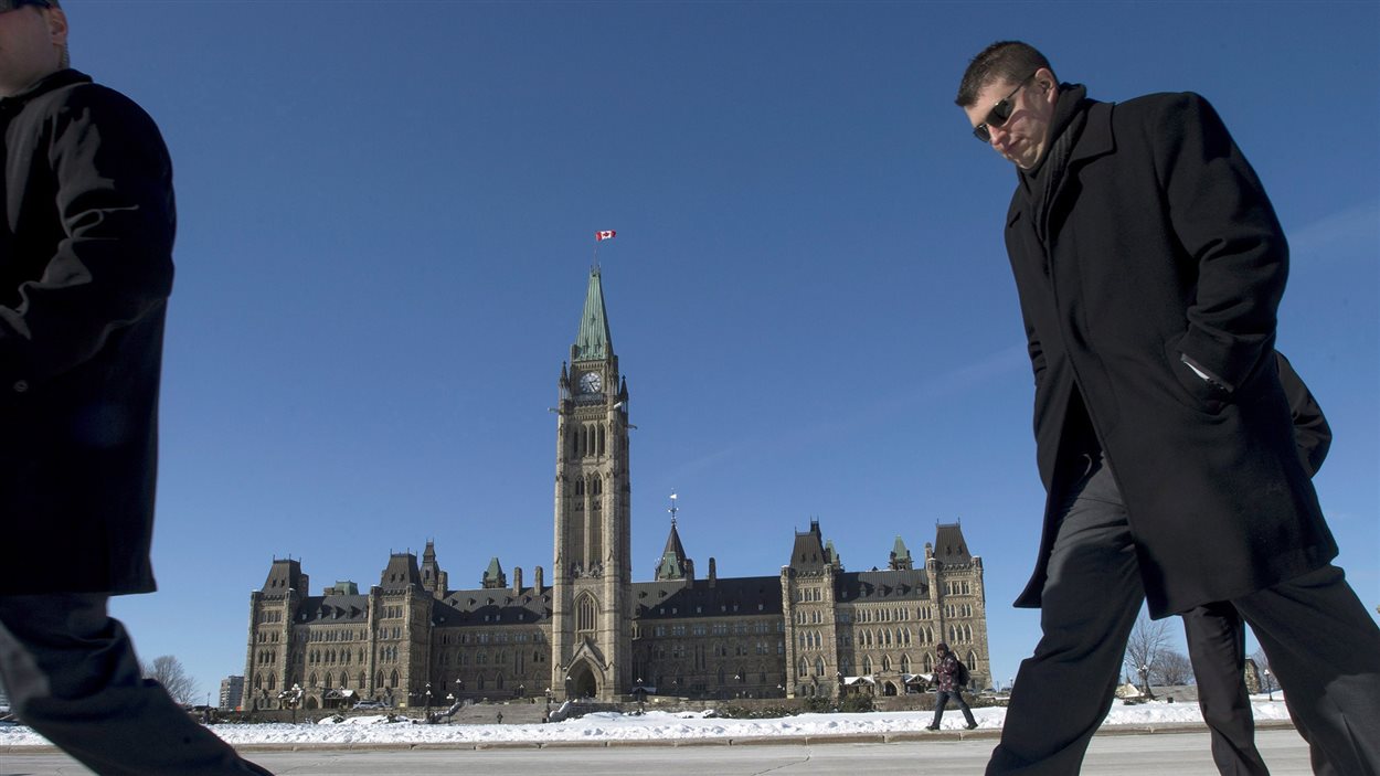 Des gens marchent devant le Parlement canadien, à Ottawa.