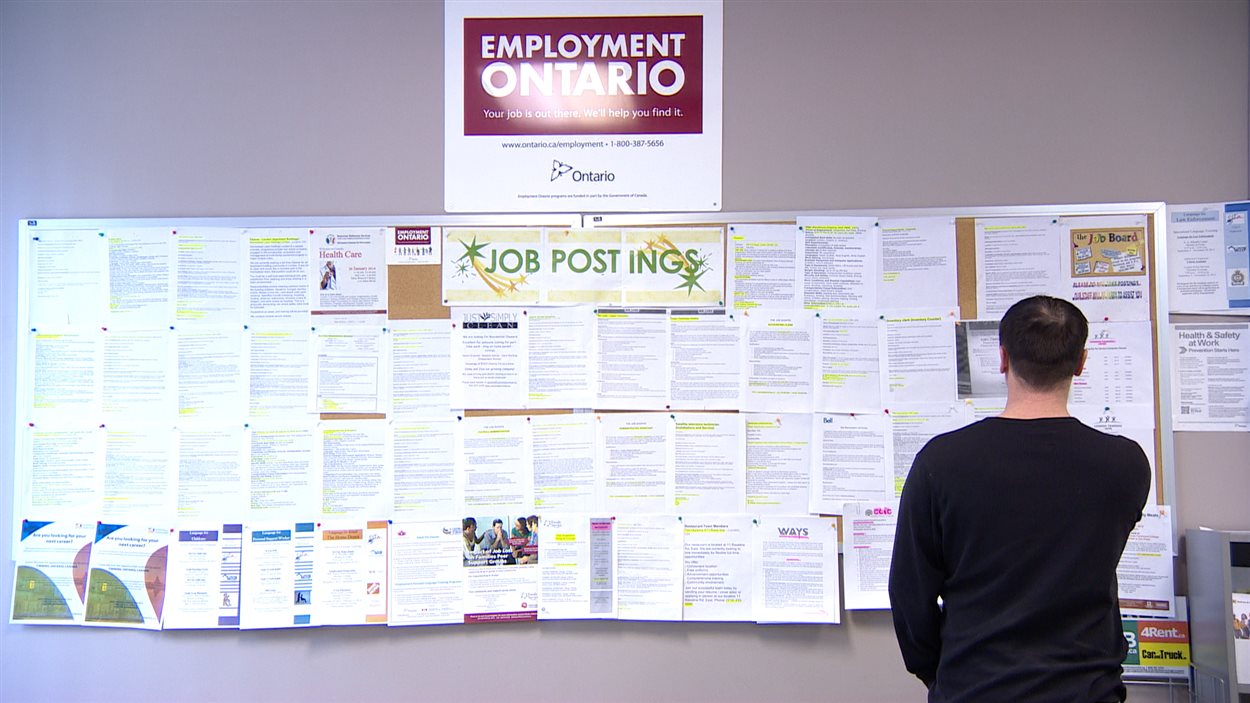 Un chômeur examine des offres d'emploi sur un babillard, à London, en Ontario.