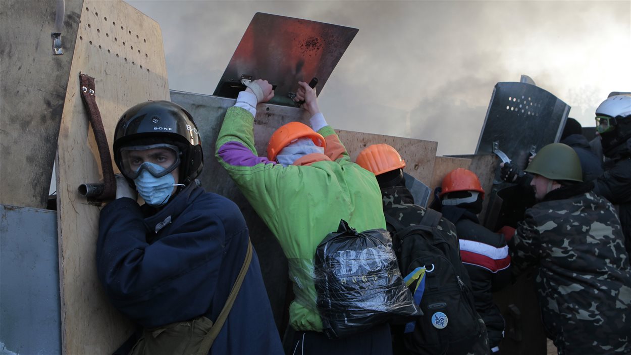 Des manifestants se protègent derrière des barricades, à Kiev.