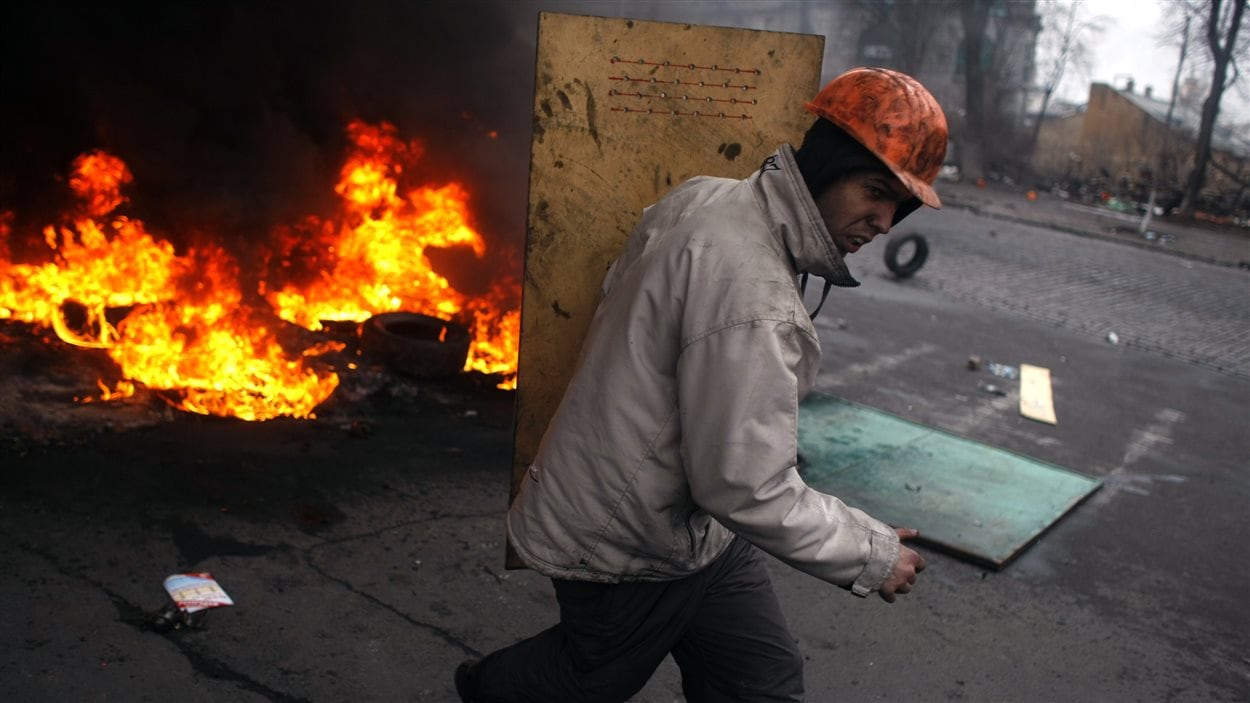 Un manifestant se protège tout près d'un incendie.