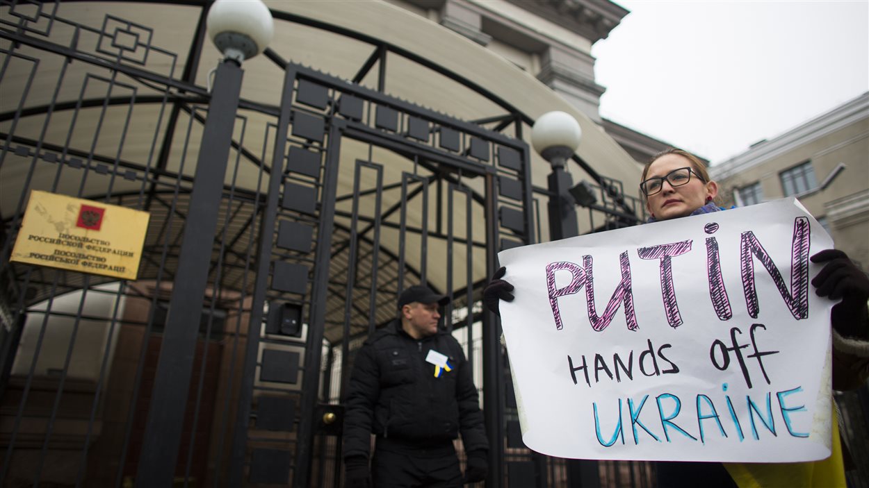 Une Ukrainienne manifeste devant l'ambassade russe à Kiev. « Poutine, touche pas à l'Ukraine », peut-on lire.
