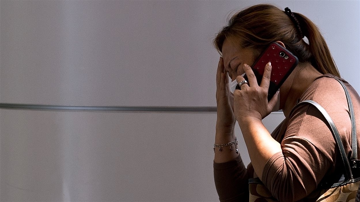Une femme parle au téléphone dans le centre de crise organisé pour les proches des disparus à l'aéroport de Kuala Lumpur, le 8 mars 2014