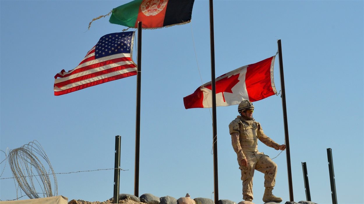 Pte. Danny Drapeau, of Alpha Company 1st Battalion Royal 22e Regiment, waits to lowers the Canadian flag for the last time at Forward Un soldat canadien s'apprête à mettre le drapeau canadien en berne à la base de Zangabad, en Aghanistan, lors du retrait des forces canadiennes de Kandahar (archives).