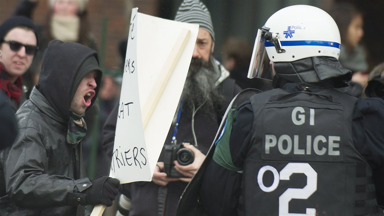 Un manifestant et un policier lors de la manifestation contre la brutalité policière à Montréal, le 15 mars 2014.