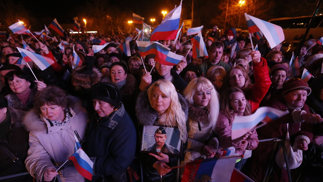 Une femme tient une photo de Vladimir Poutine en attendant les résultats du référendum sur l'avenir de la Crimée, le 16 mars 2014.