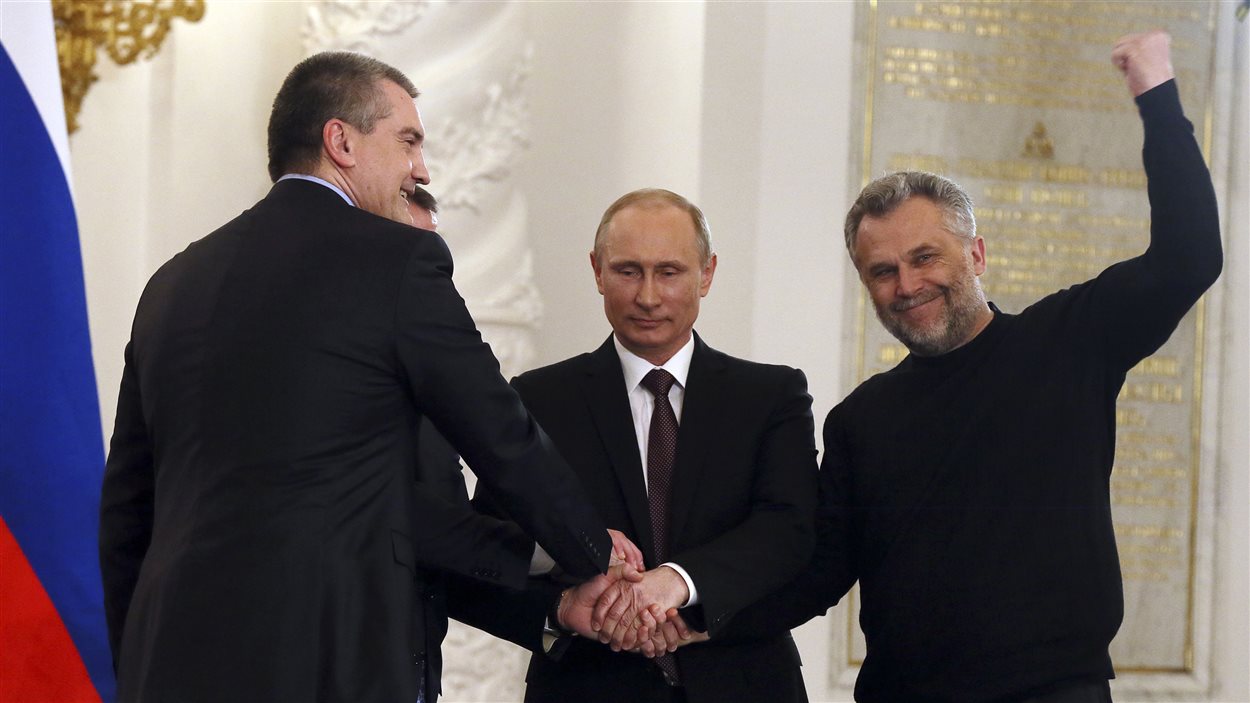 Le prédisent russe, Vladimkir Poutine, scelle par une poignée de main l'accord sur l'annexion de la Crimée avec les premier ministre de Crimée, Sergeï Aksyonov (gauche) et le maire de Sébastopol, Alexei Chaliy (droite).