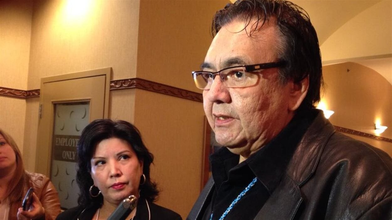 Le ministre des Affaires autochtones du Manitoba, Eric Robinson, parle aux journalistes le 24 mars 2014 à Winnipeg, sous le regard de Coleen Rajotte, une femme qui a connu la rafle d'enfants autochtones des années 1960.