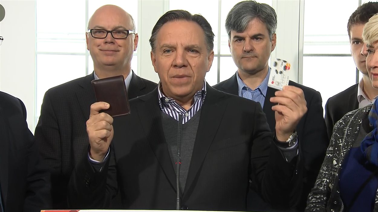 François Legault montre un portefeuille et une carte de crédit.