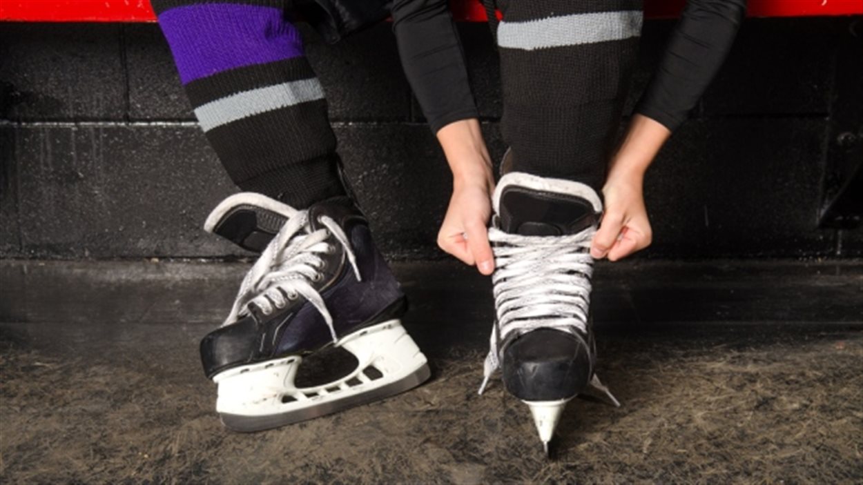 Un enfant attache ses patins de hockey