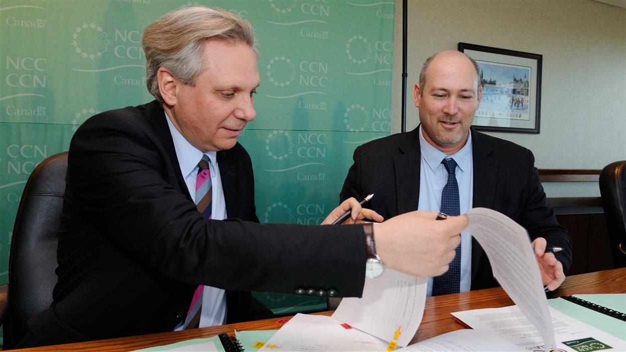 Le premier dirigeant de la CCN, Mark Kristmanson et le président-directeur général de CycleHop, Josh Squire officialisent le transfert des services Bixi.