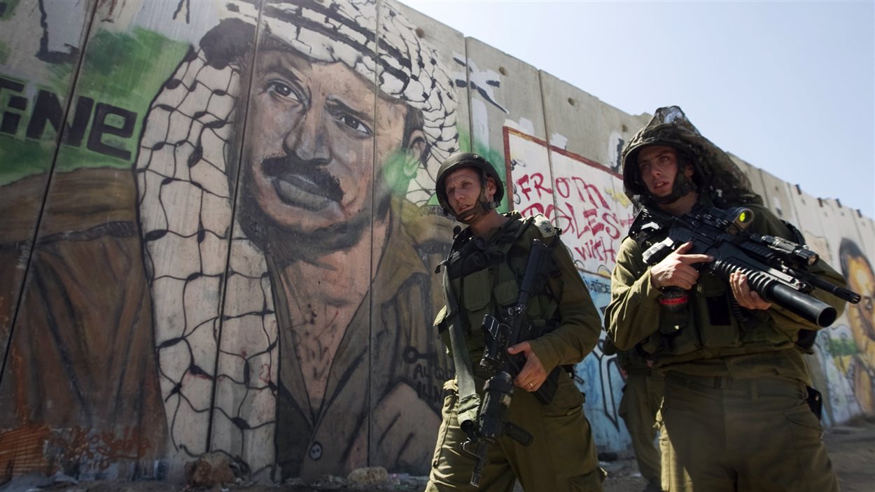 Des soldats israéliens devant le mur construit par Israël autout de la Cisjordanie.