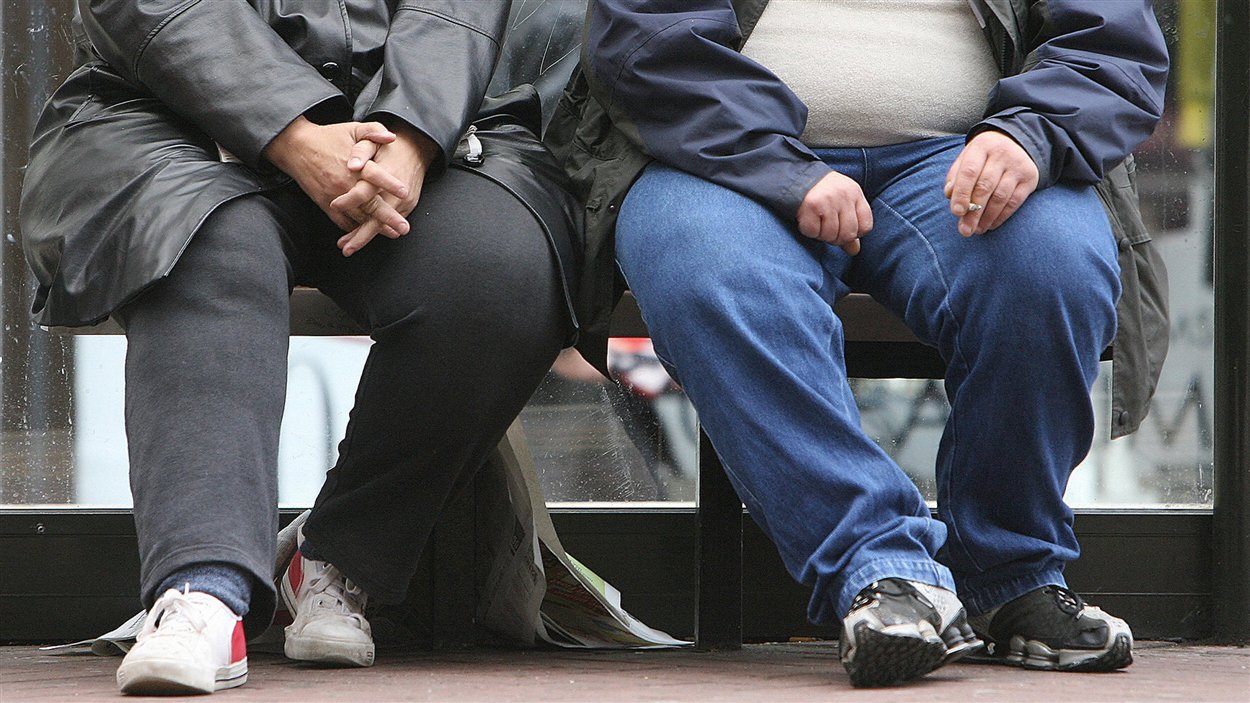Un homme et une femme souffrant d'obésité attendent dans un abri d'autobus.