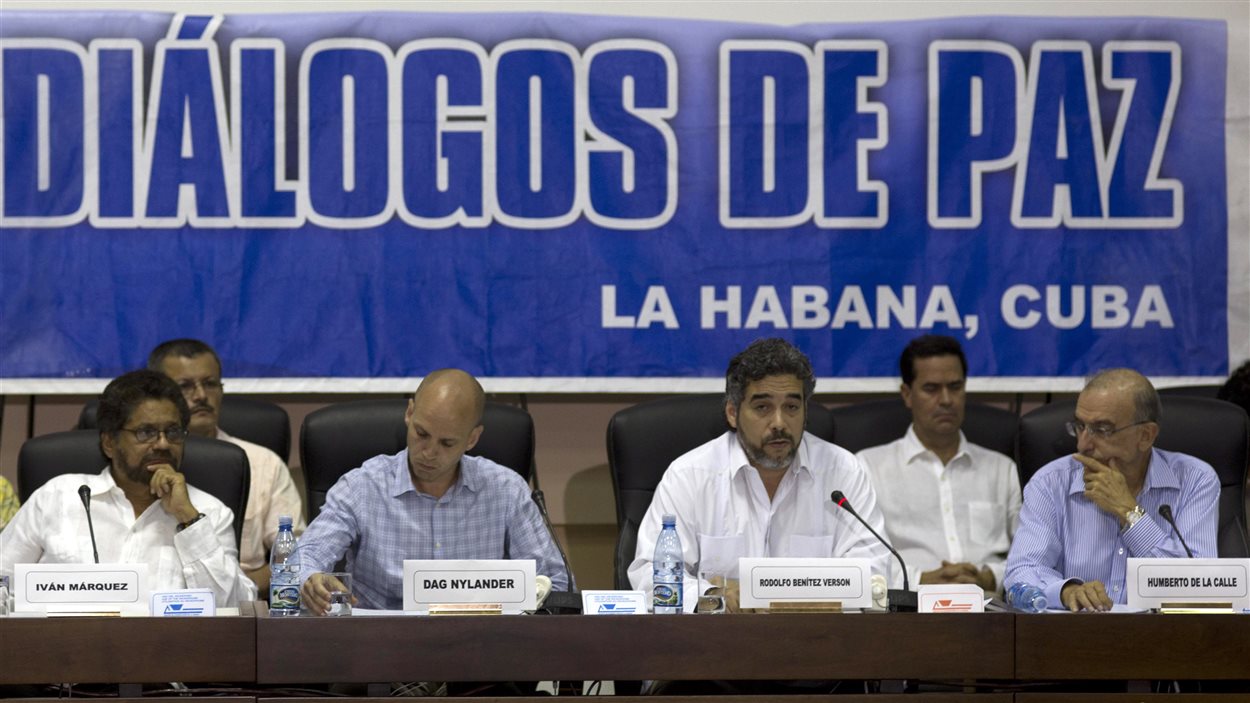 Le négociateur en chef des FARC, Ivan Marquez (gauche) et le négociateur pour le gouvernement colombien, Humberto de la Calle (droite) écoutent le représentant cubain pour les pourparlers de paix, Rodolfo Benitez Verson, qui fait la lecture du texte de l’accord, à La Havane, le 16 mai.