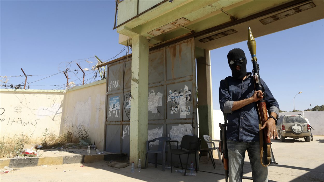 Un milicien libyen se tient devant l'entrée d'un camp d'entraînement le 17 mai, au lendemain d'affrontements mortels avec les autorités