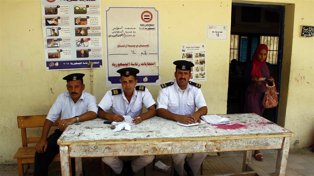 Des policiers égyptiens chargés de vérifier l'identité des électeurs à un bureau de vote du Caire attendent leur prochain client.