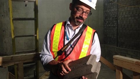 Le Dr David Roberge, chef du département de la radio-oncologie, montre une brique de ciment et de métaux qui compose les murs de la radiothérapie et qui protège de la radioactivité.
