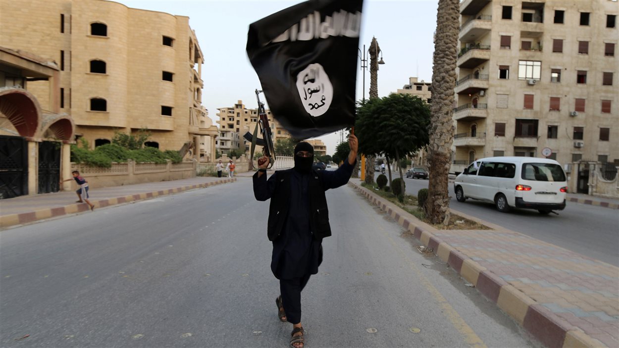 Un militant de l'État islamique brandit un drapeau du «califat» dans la ville syrienne de Saqqa.