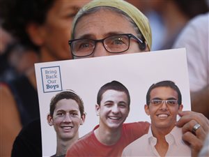 Une femme montre une photo des trois jeunes hommes lors d'un rassemblement à Tel-Aviv, le 29 juin.