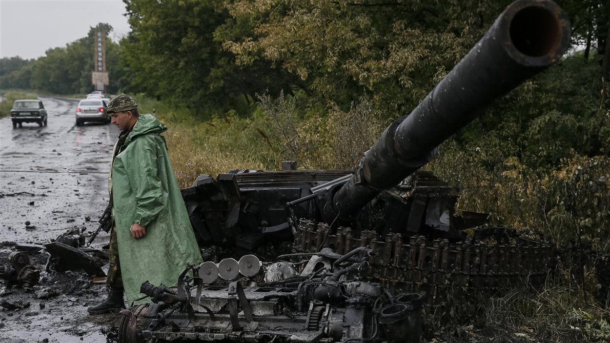 Un soldat ukrainien près de ce qui reste d'un blindé des séparatistes prorusses