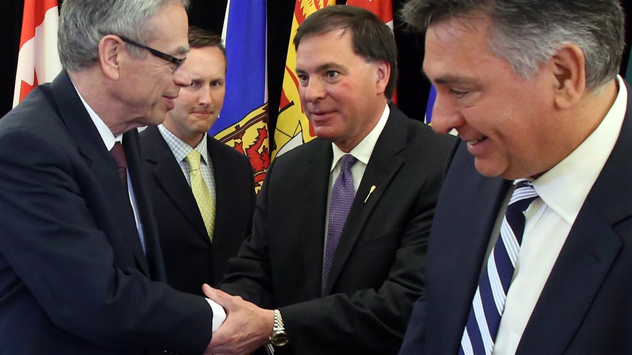 Le ministre des Finances du Canada, Joe Oliver (gauche), serre la main au ministre de la Justice de la Saskatchewan, Gordon Wyant (centre), en compagnie du ministre de la Justice du Nouveau-Brunswick, Troy Lifford et du ministre des Finances de l’Ontario, Charles Sousa, après la signature d’un accord sur la création d’un organisme national de valeurs mobilières coopératif à Ottawa, le 9 juillet 2014.