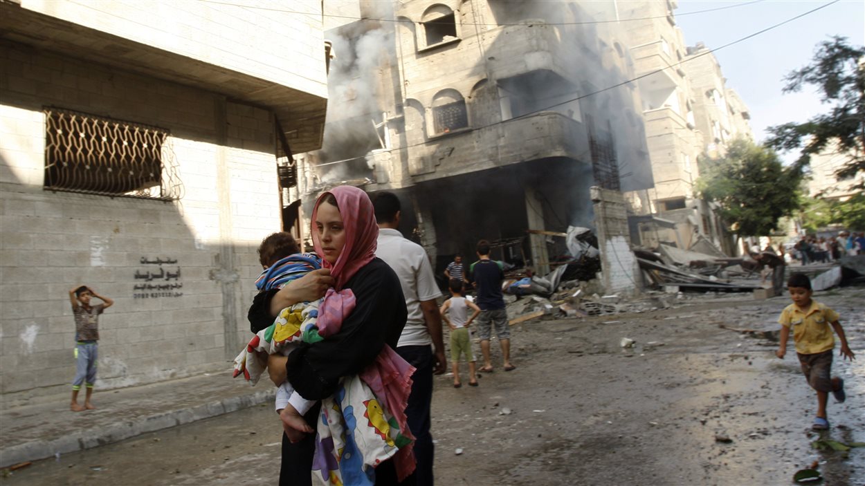 Une Palestinienne fuit un bombardement avec son enfant dans les bras dans la ville de Gaza.