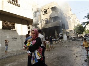 Une Palestinienne fuit un bombardement avec son enfant dans les bras dans la ville de Gaza.