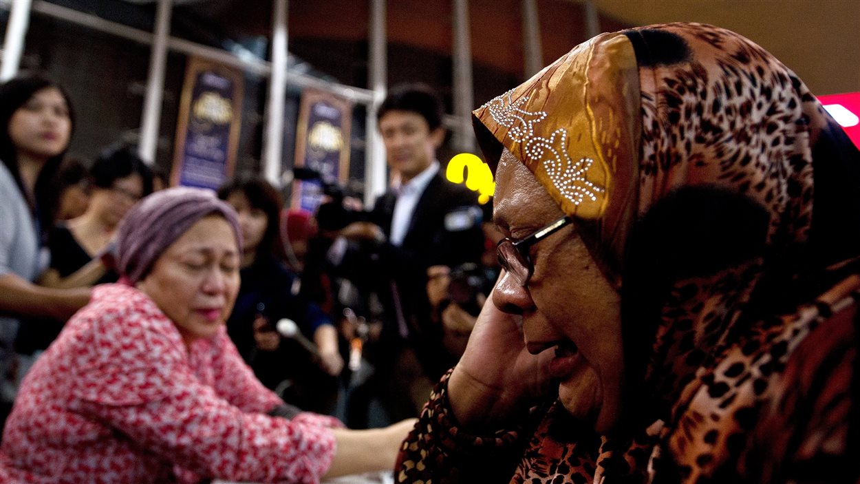 À l'aéroport de Kuala Lumpur, une femme en pleurs au téléphone.