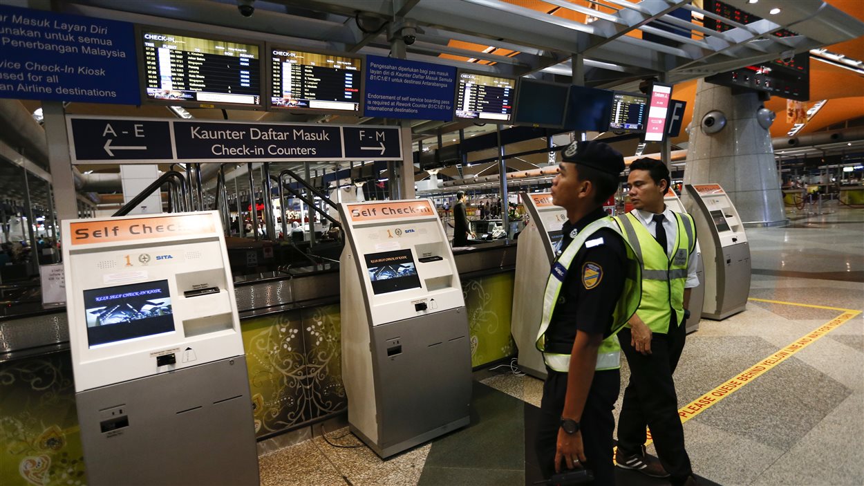 Les employés de l'aéroport de Kuala Lumpur regardent les informations sur le vol de la Malaysia