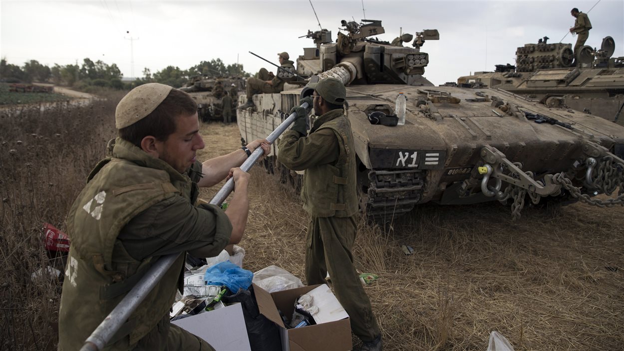 Les soldats israéliens entretiennent leur tank, à la frontière avec Gaza