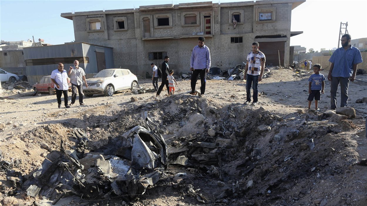 Des gens contemplent les restes d'un avion de guerre écrasé à Benghazi, le 29 juillet 2014