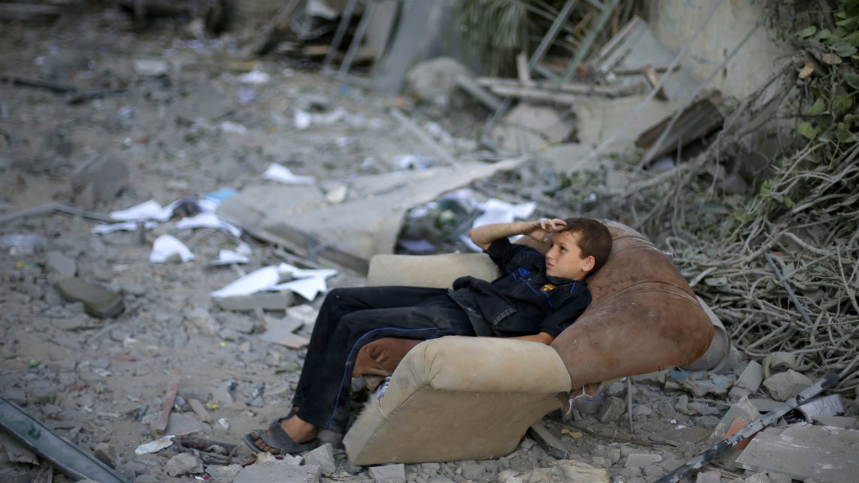 Un jeune Palestinien s'est assis sur un sofa, le 2 août, à côté de ce qui était autrefois la maison familiale.