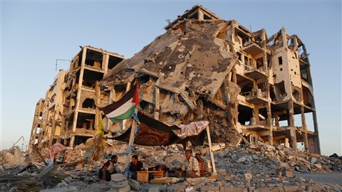 Des Palestiniens devant un immeuble détruit dans la bande de Gaza.