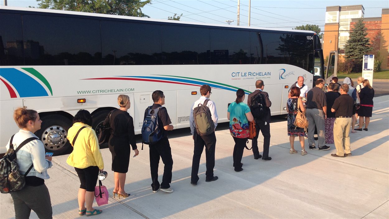 Des usagers embarquent dans un autobus au nouveau stationnement incitatif de Candiac