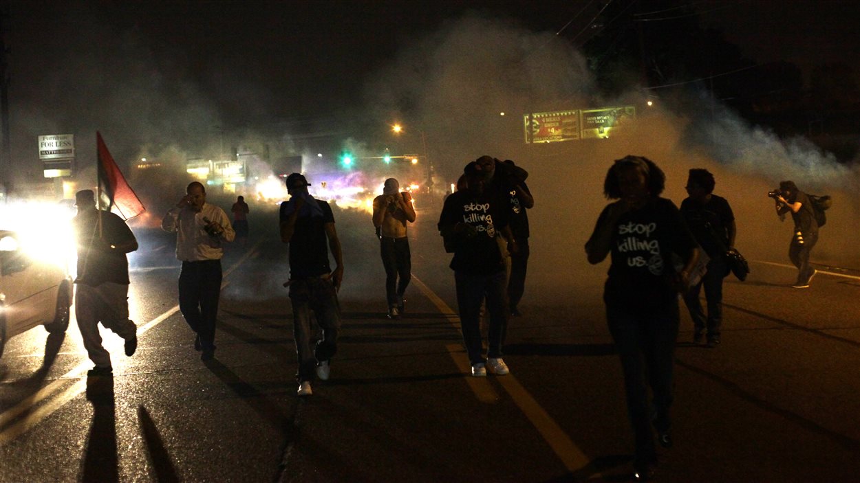 Des manifestants se dispersent après que la police eut lancé des gaz lacrymogènes et des fumigènes, dimanche, avant même le début du couvre-feu.