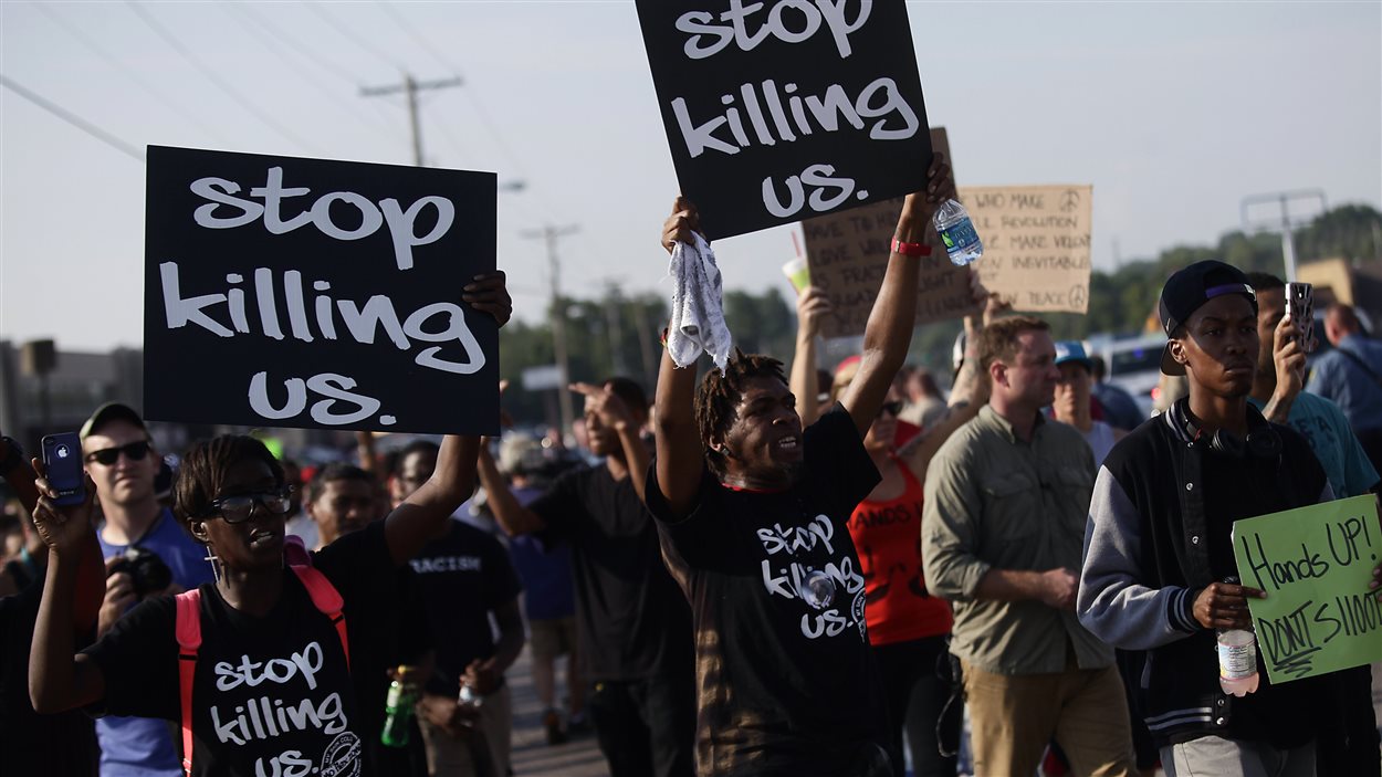 Des manifestants brandissent des pancartes où on peut lire « Arrêtez de nous tuer », à Ferguson le 18 août 2014.