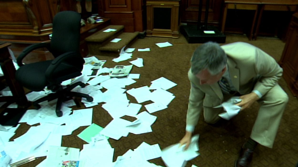 Un employé ramasse les papiers laissés par les manifestants à l'hôtel de ville de Montréal, le 18 août 2014.