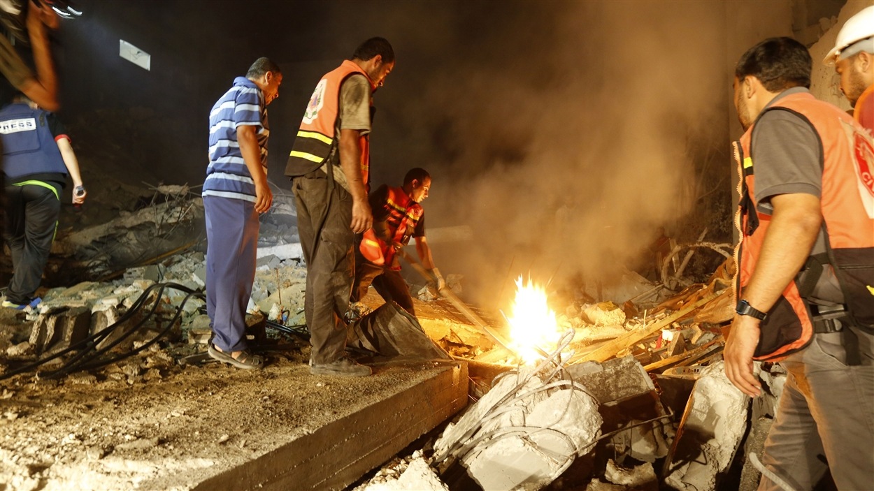 Des secouristes palestiniens inspectent les décombres après l'explosion d'un roquette israélienne.