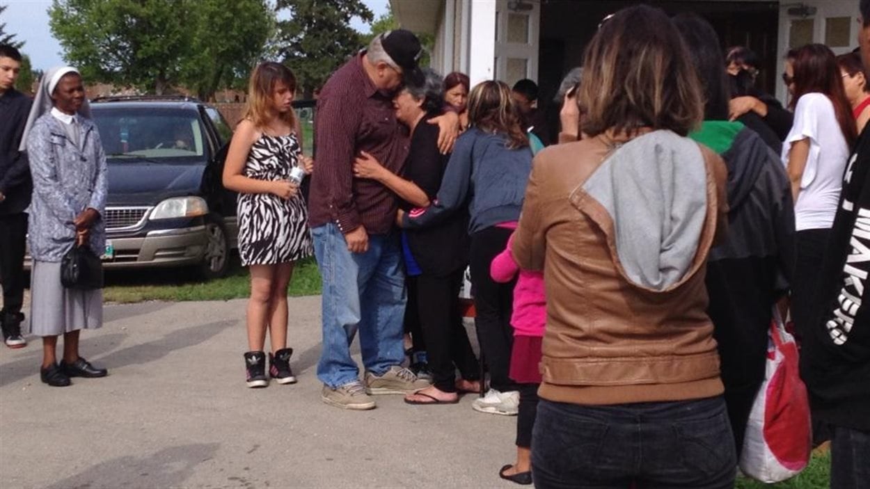 Un homme réconforte une femme en pleurs à la sortie des funérailles de Tina Fontaine, le 23 août 2014 à Sagkeeng, au Manitoba.
