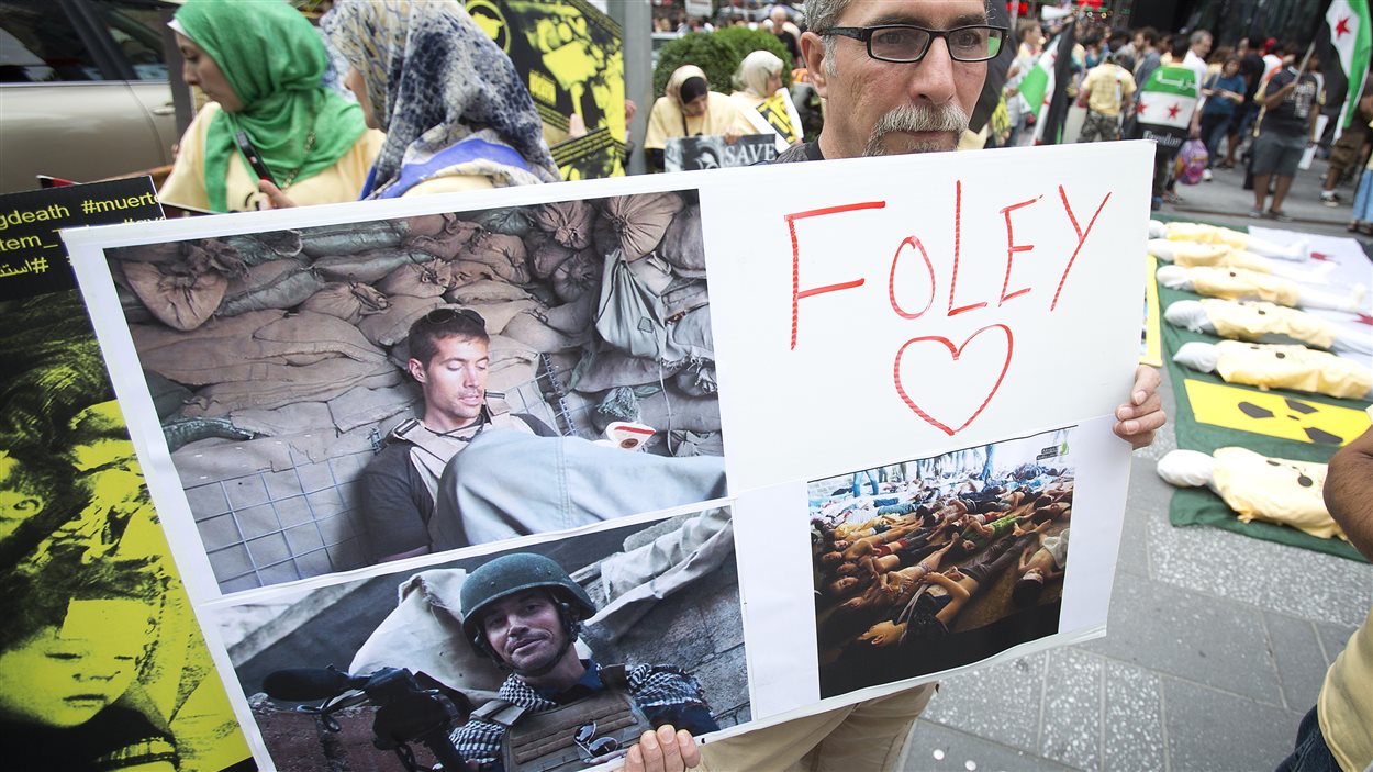 Un homme tient un affiche à la mémoire de James Foley, lors d'une manifestation à Times Square contre le régime de Bachar Al-Assad (23 août 2014).